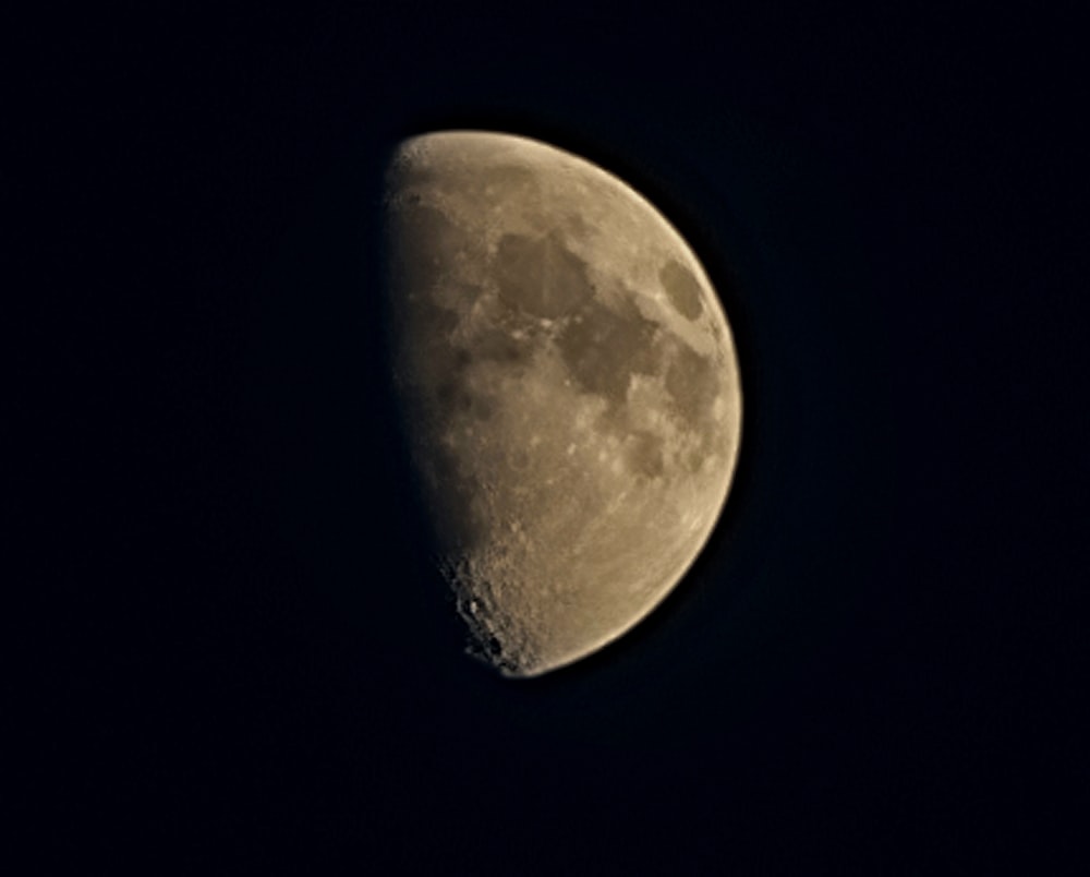 a half moon is seen in the dark sky