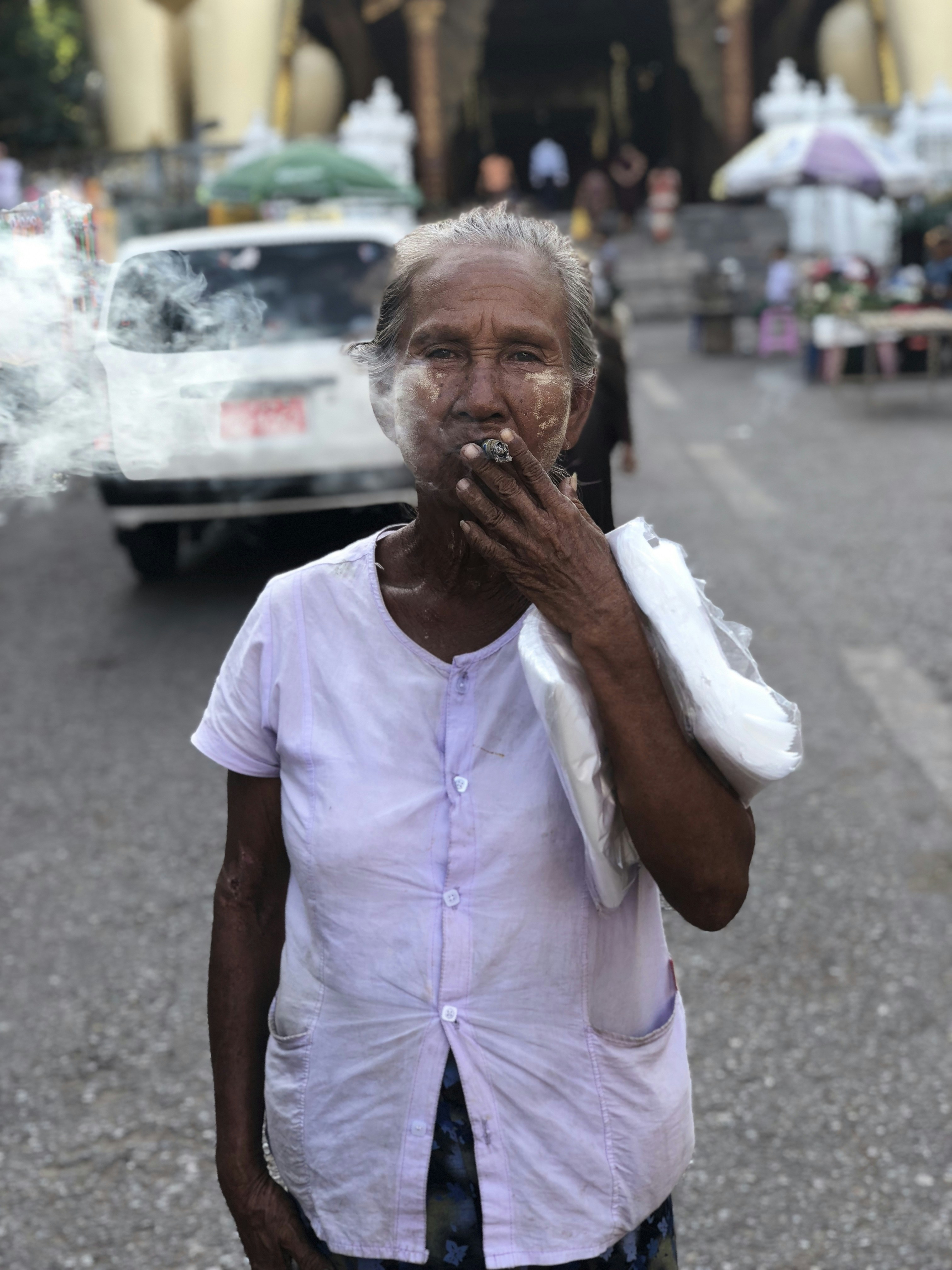 an old woman smoking a cigarette on the street