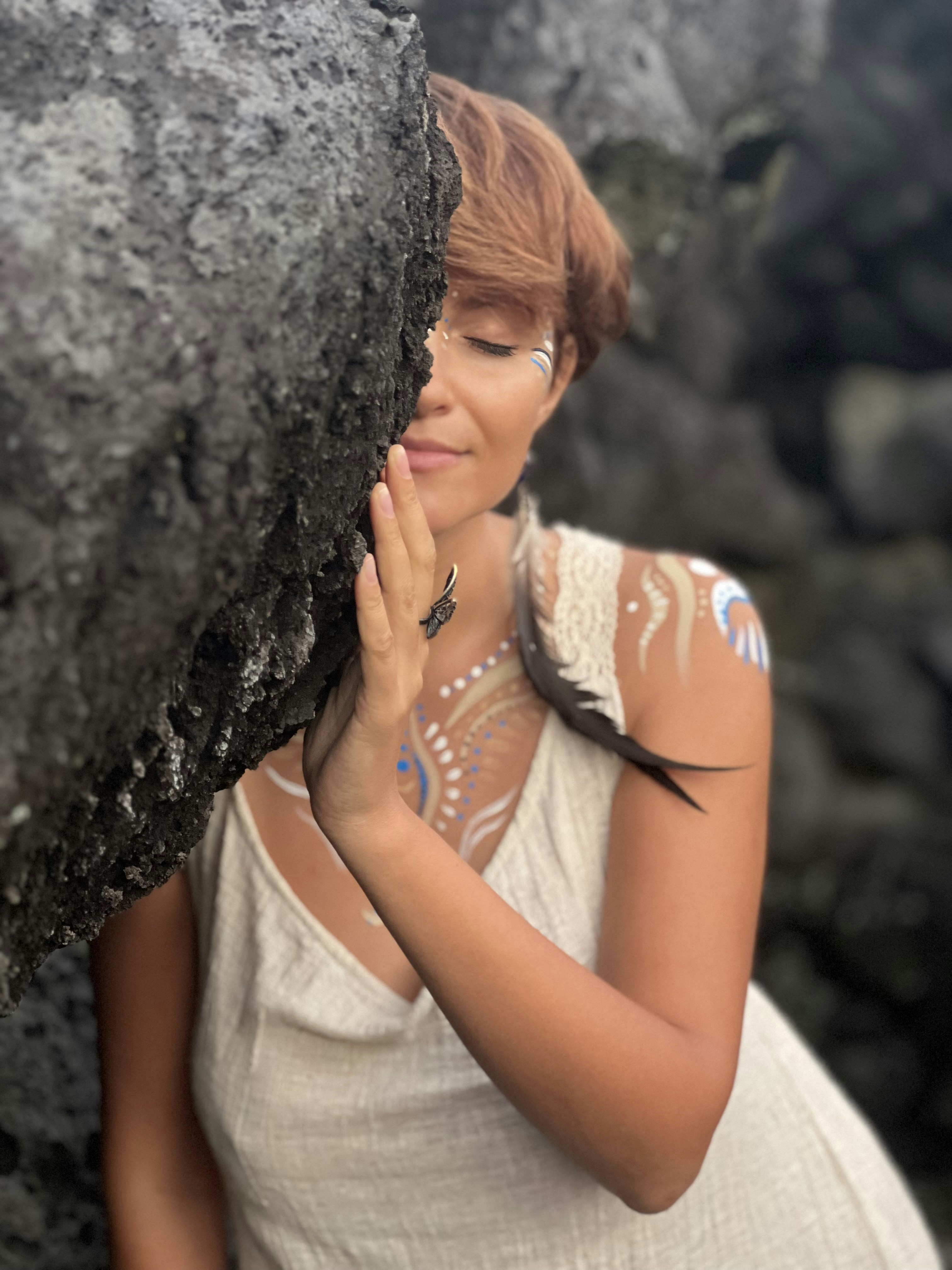 a woman standing next to a large rock
