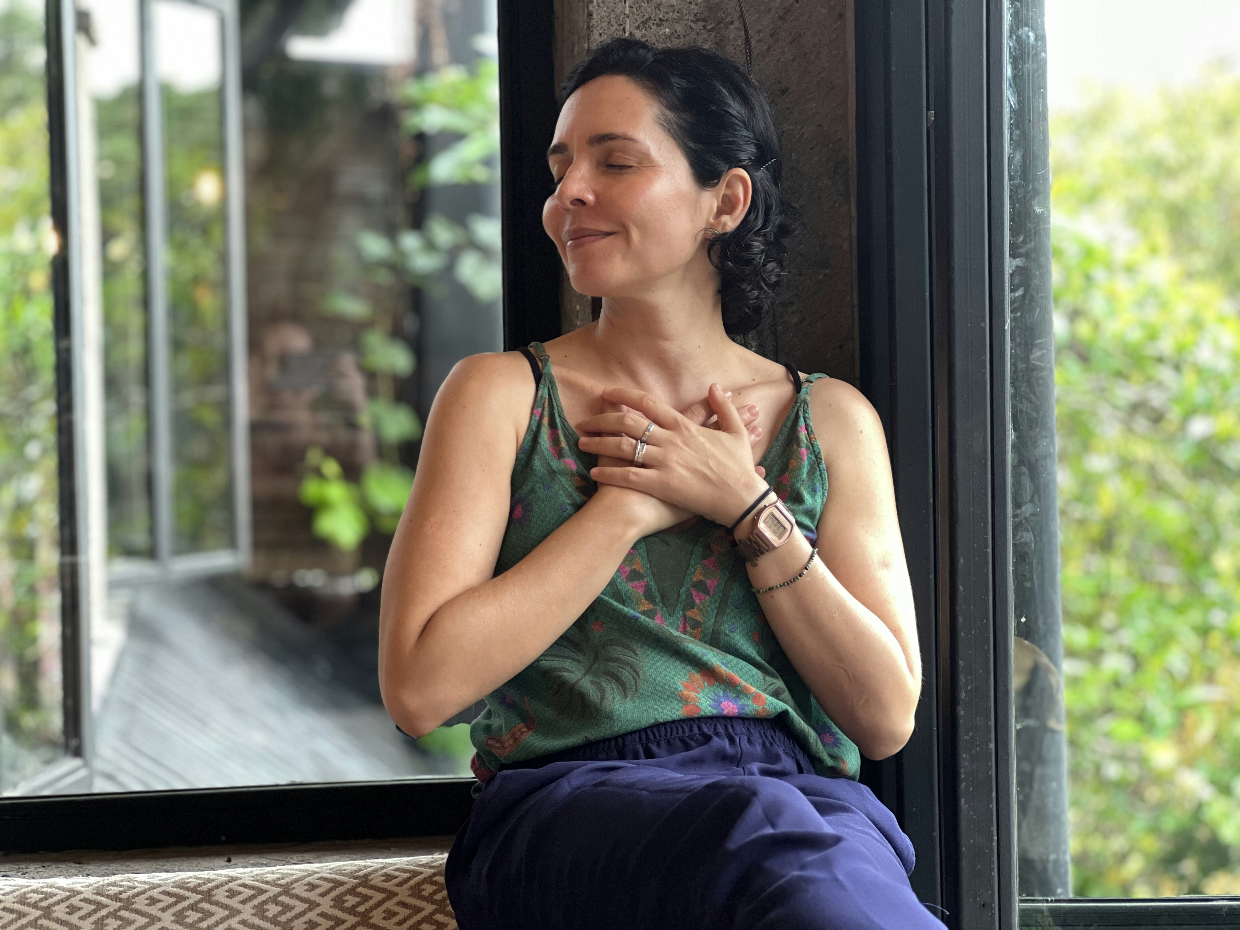 a woman sitting on a window sill with her hands folded