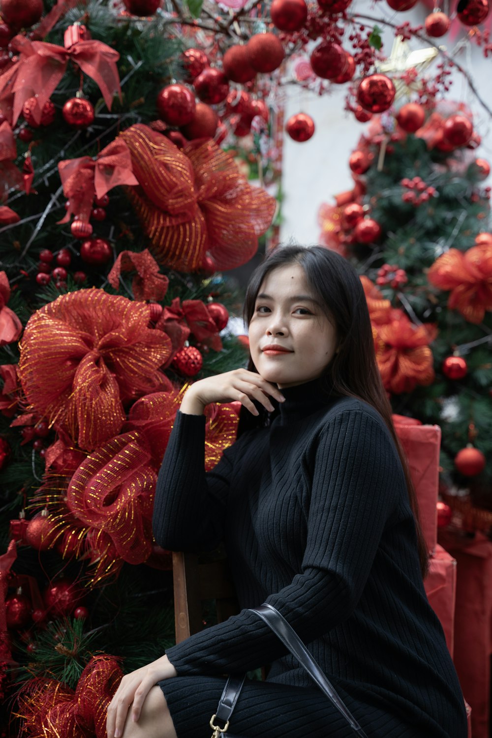 a woman sitting on a chair in front of a christmas tree