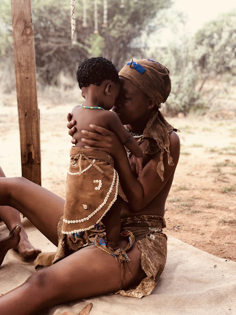 a woman sitting on the ground holding a child