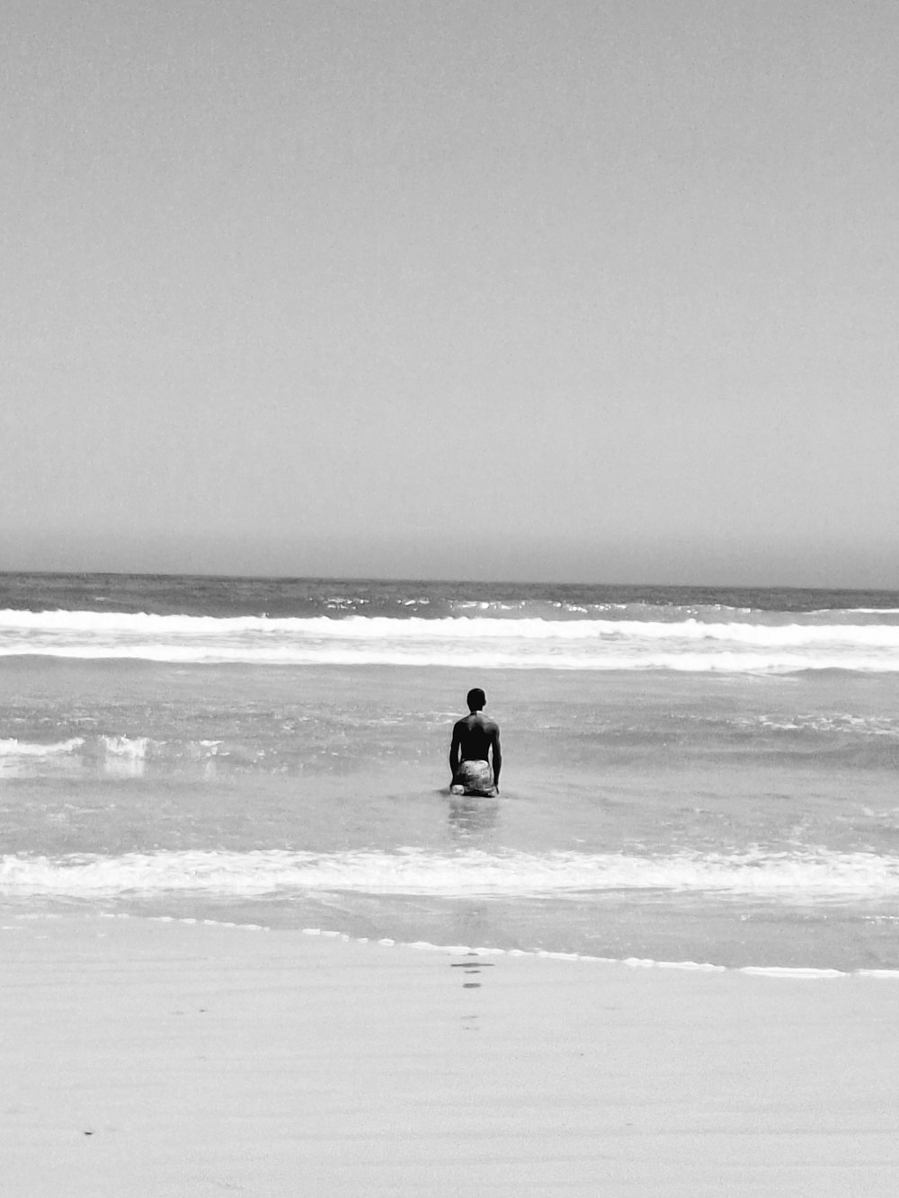 Ein Mann sitzt auf einem Surfbrett im Meer