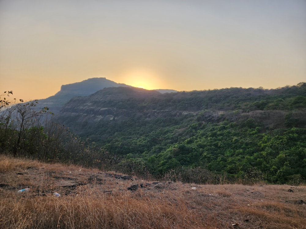 the sun is setting over the mountains in the distance