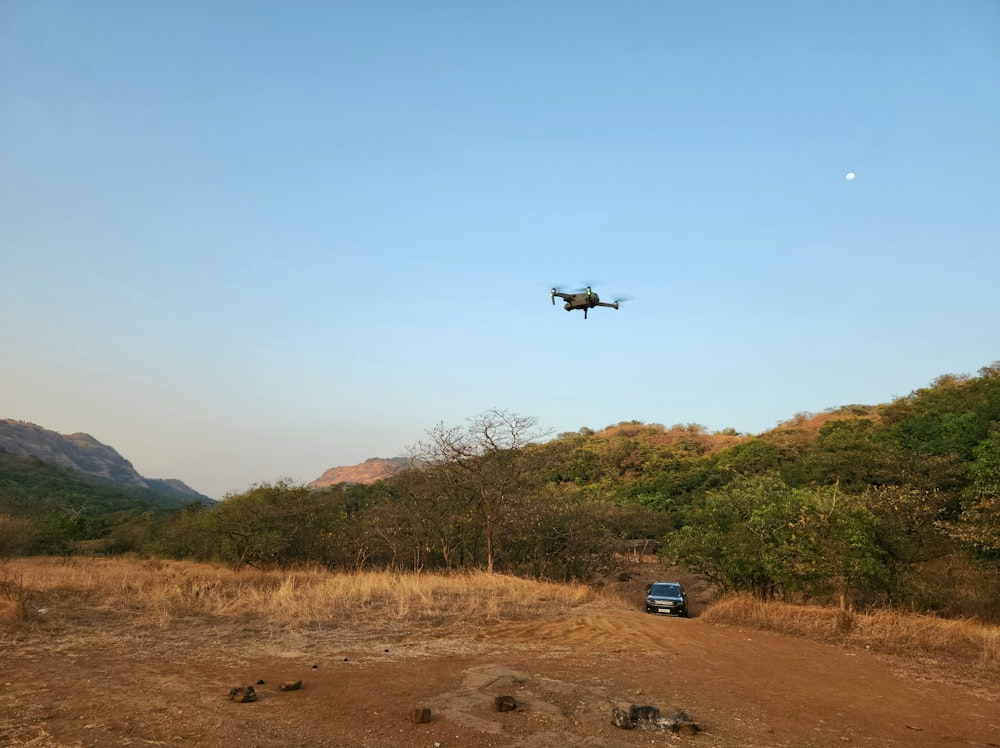 a small plane flying over a dirt road