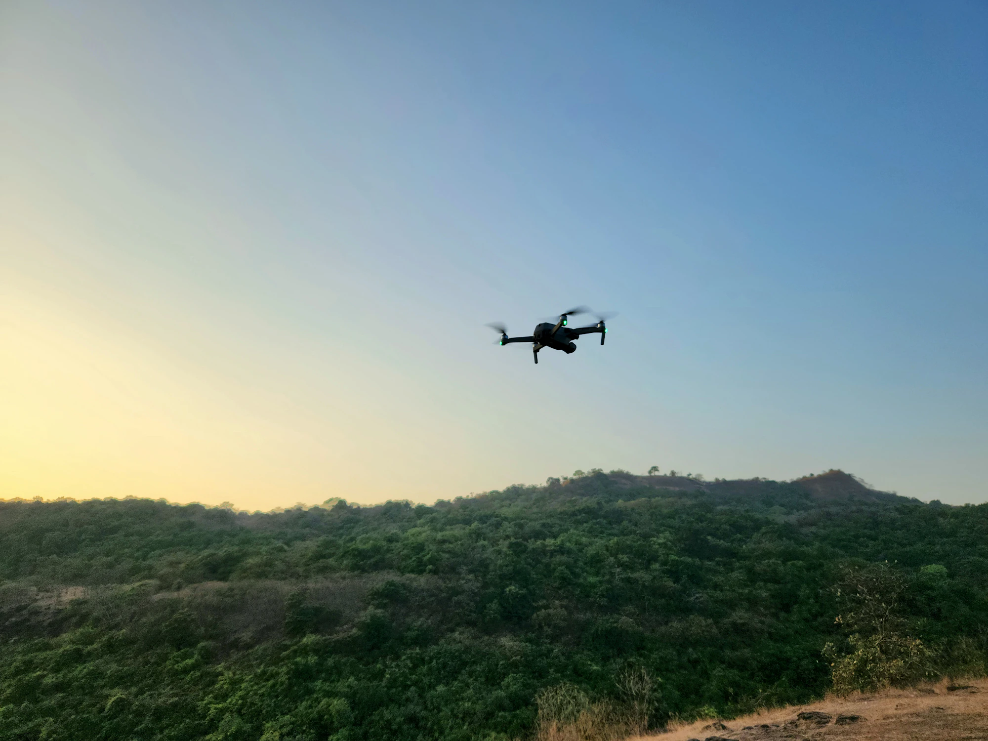 A long-endurance drone over green hills at dusk.