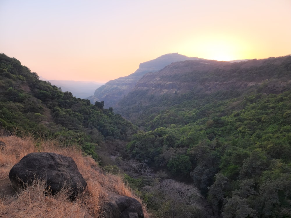 the sun is setting over the mountains and trees