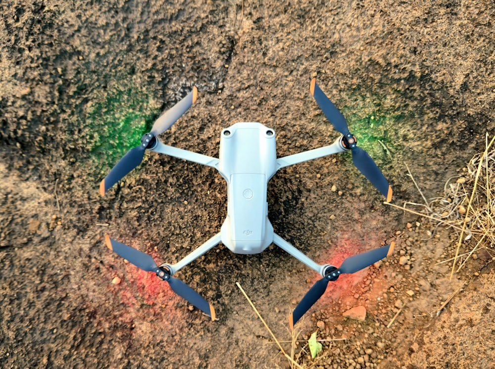 a blue and white remote controlled flying device in the dirt