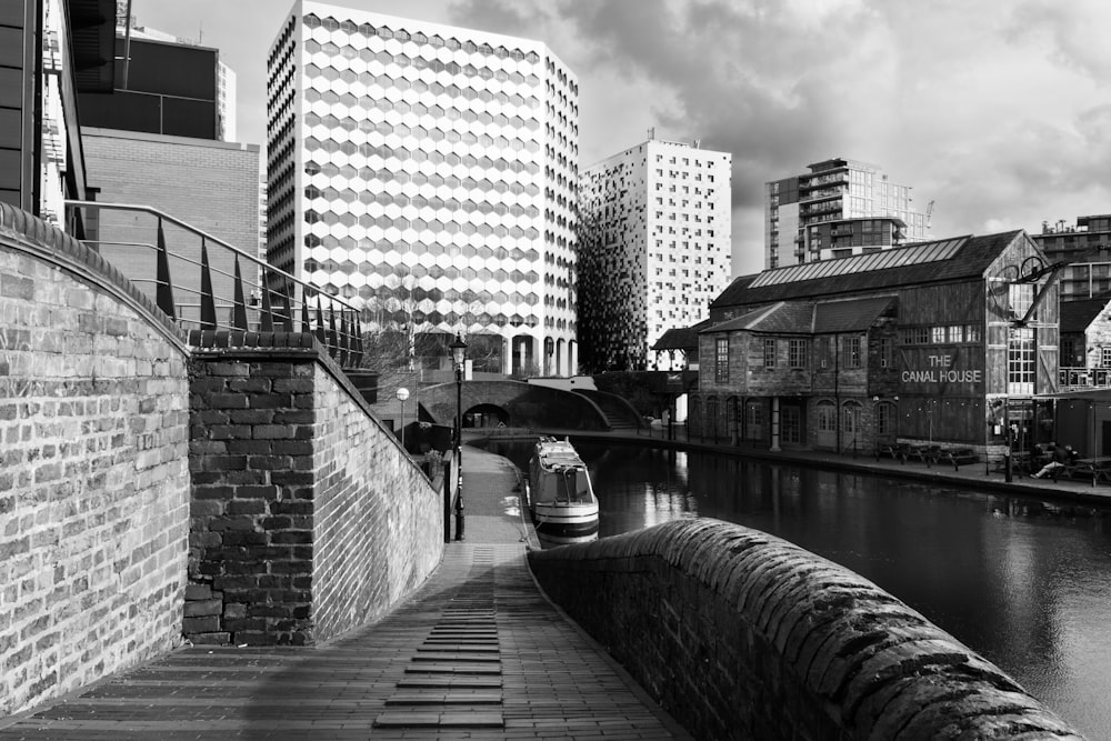 a black and white photo of a canal in a city