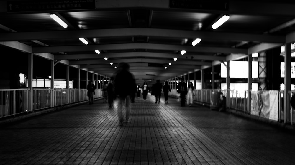 a black and white photo of people walking down a walkway