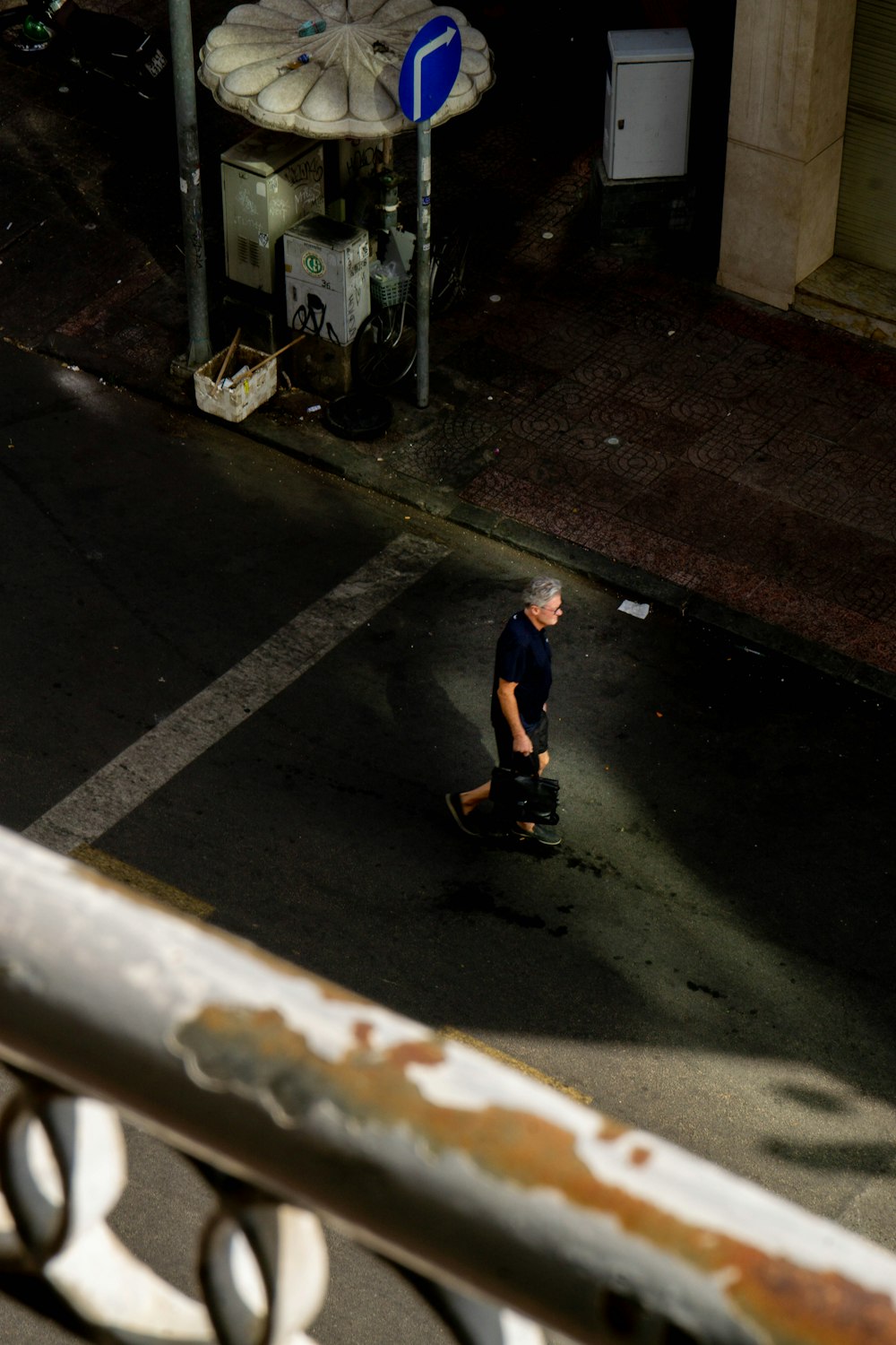 a man walking across a street next to a parking meter