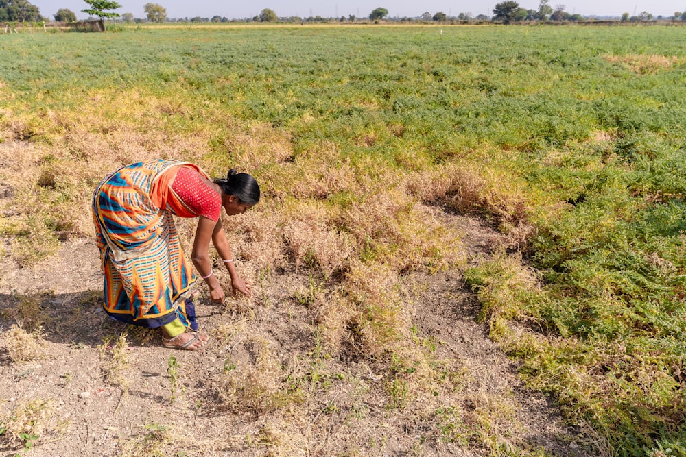 a woman kneeling down in the middle of a field