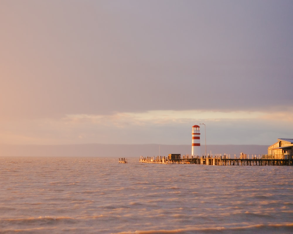 a red and white light house sitting on top of a body of water