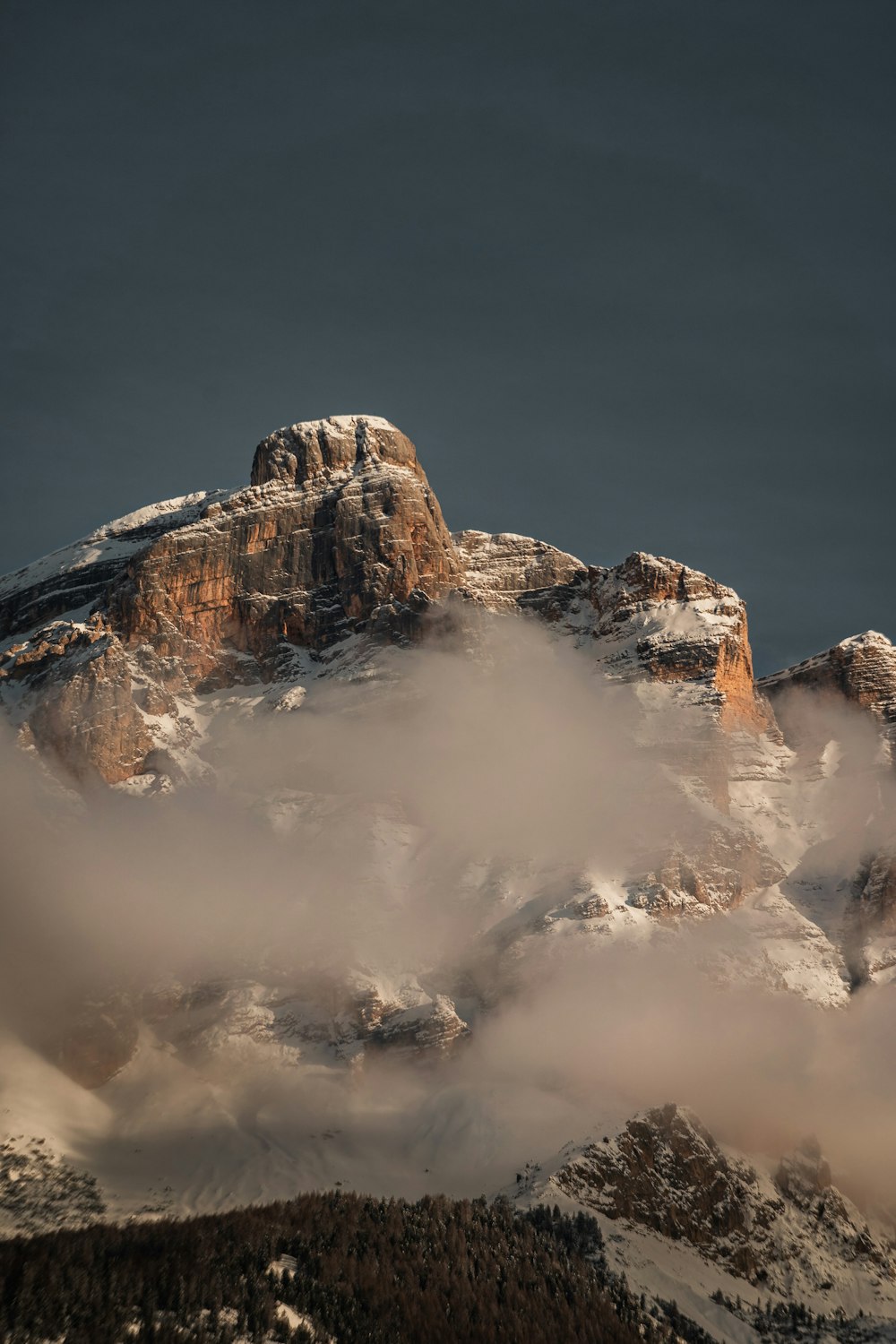 a mountain covered in snow under a cloudy sky