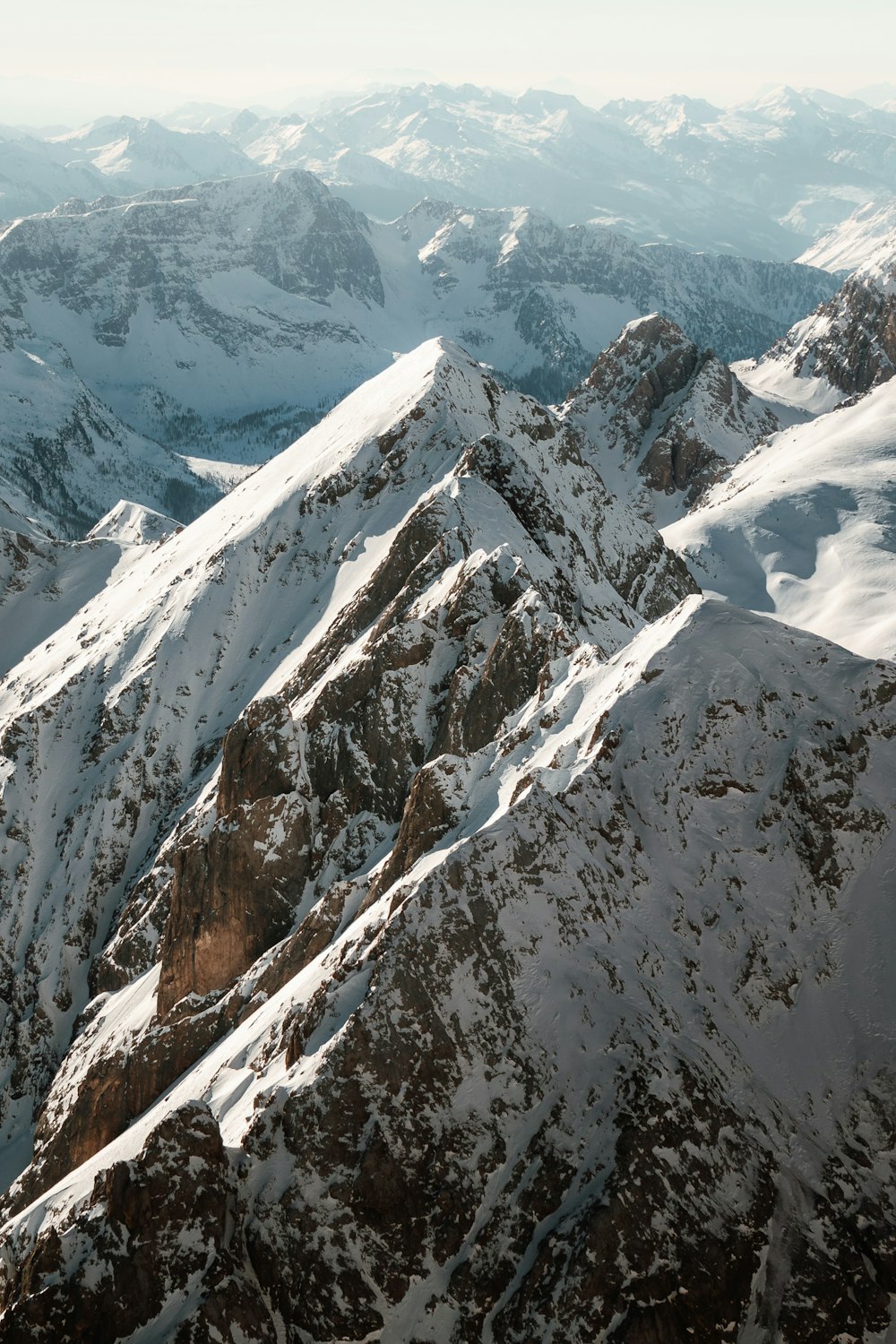 a mountain range covered in snow with mountains in the background