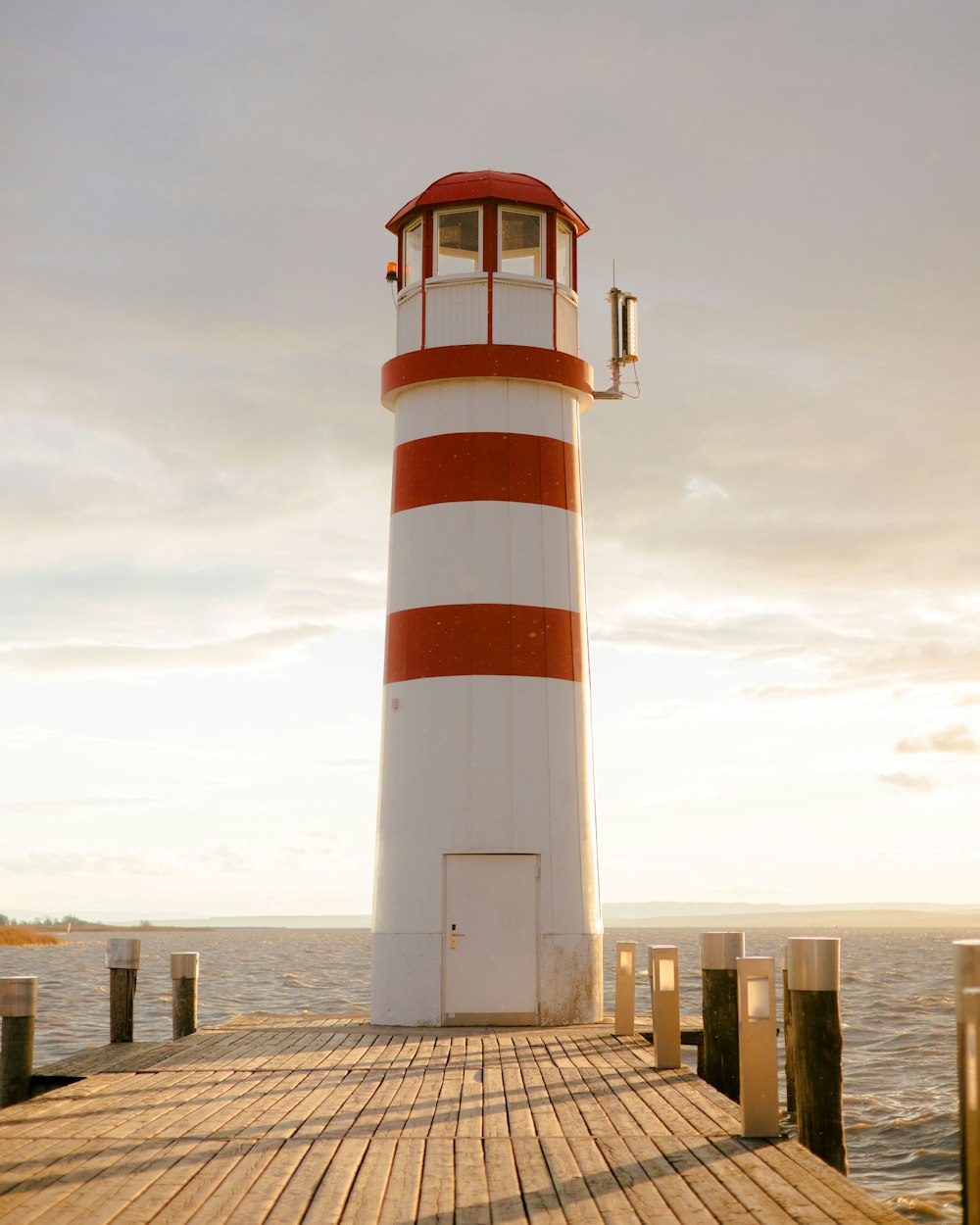 a red and white lighthouse sitting on top of a wooden pier
