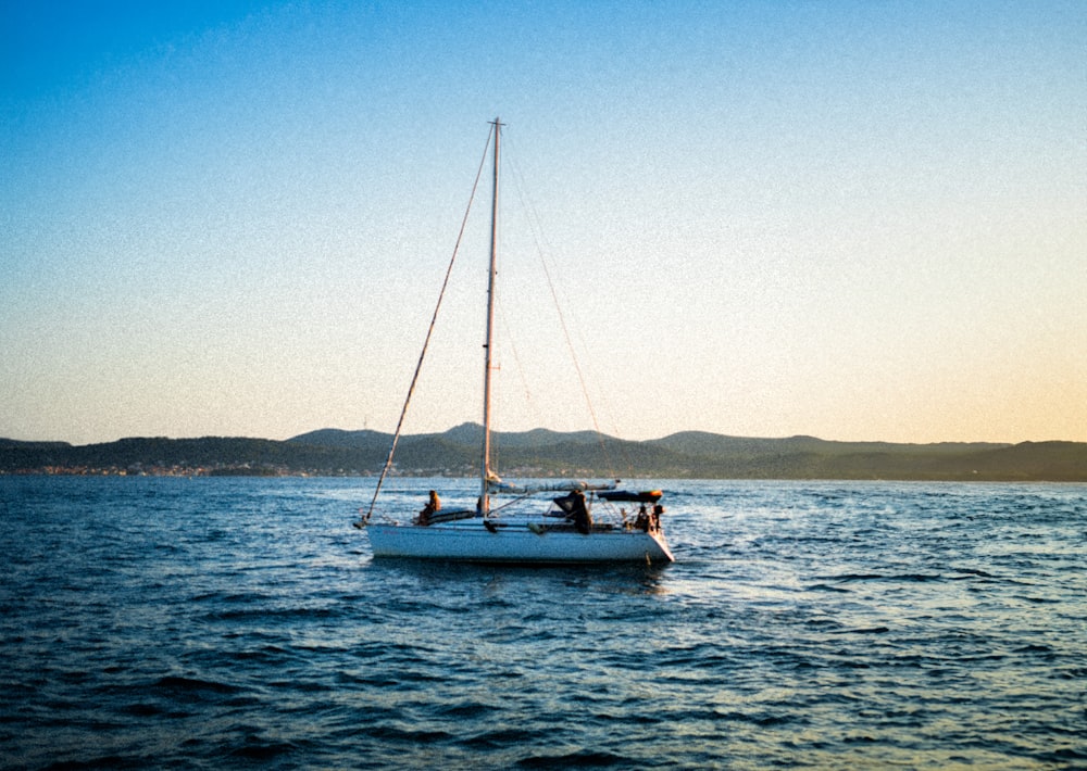 a sailboat with two people on it in the water