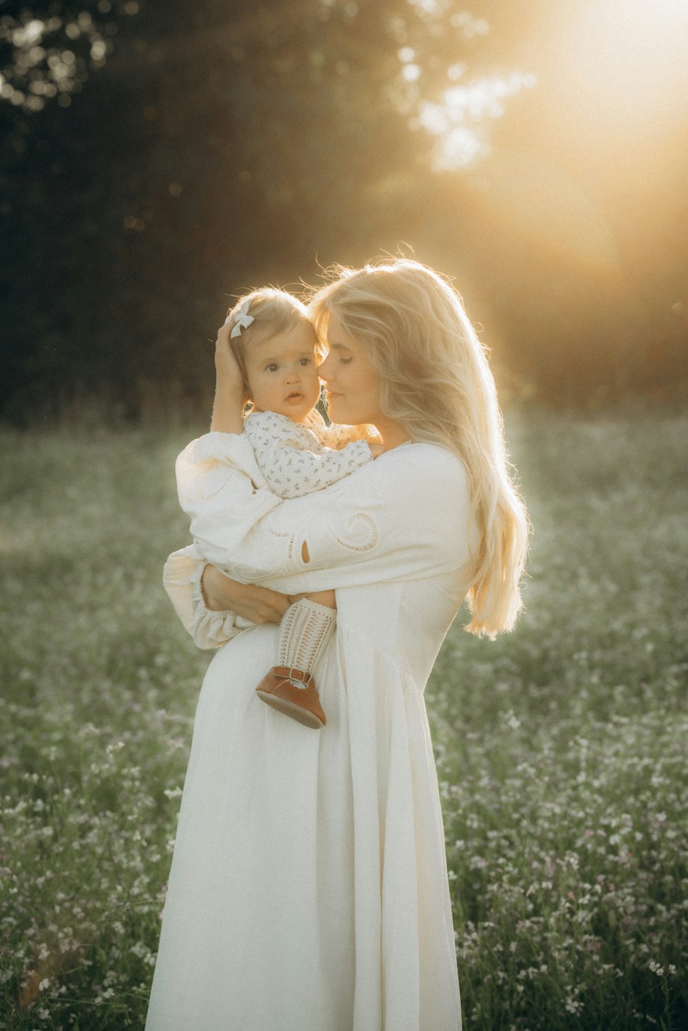 a woman holding a baby in a field