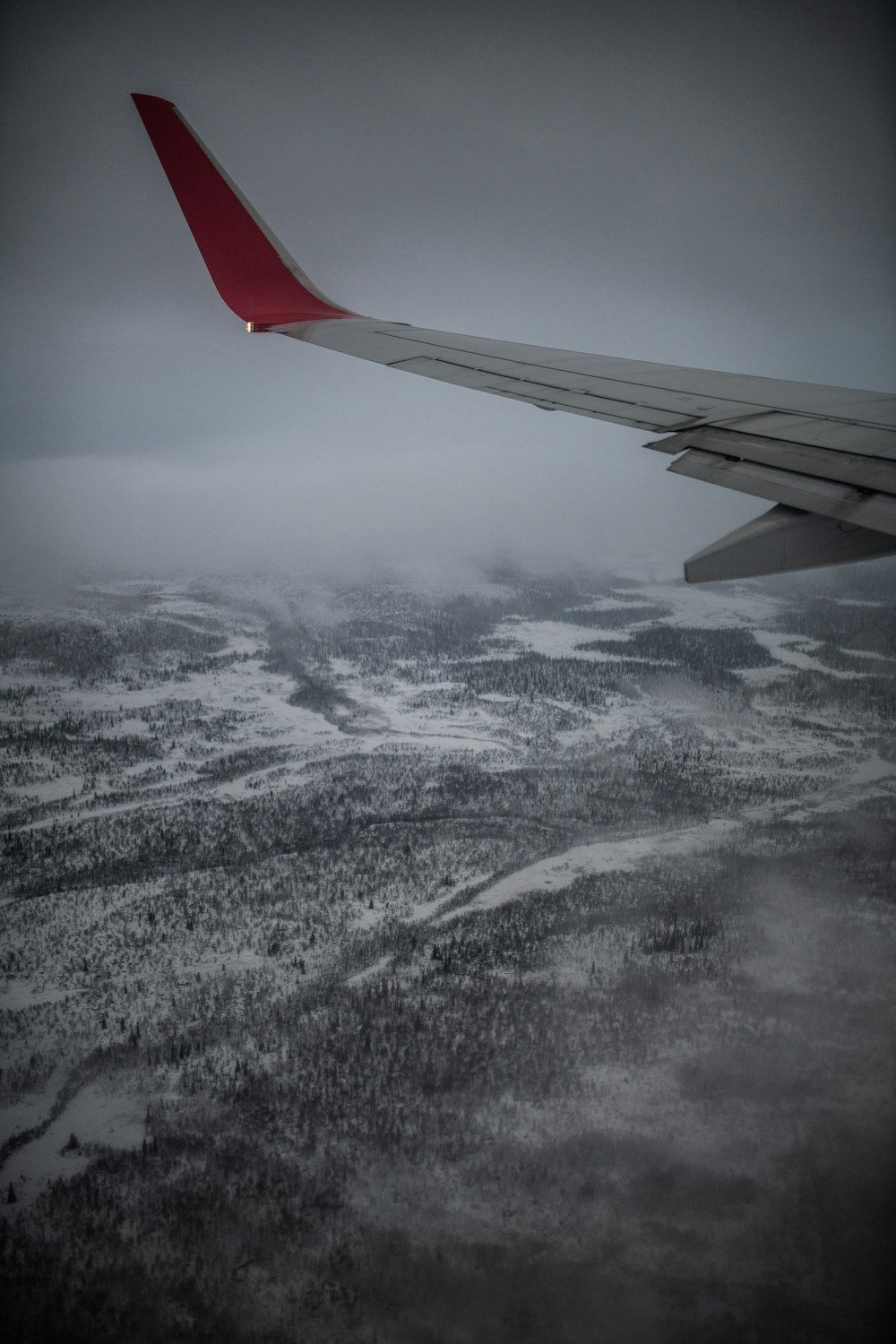 the wing of an airplane flying over a snowy landscape