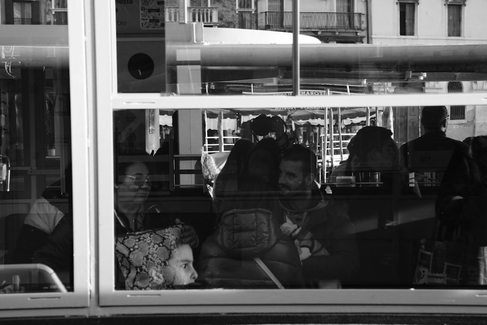 a black and white photo of people sitting in a bus