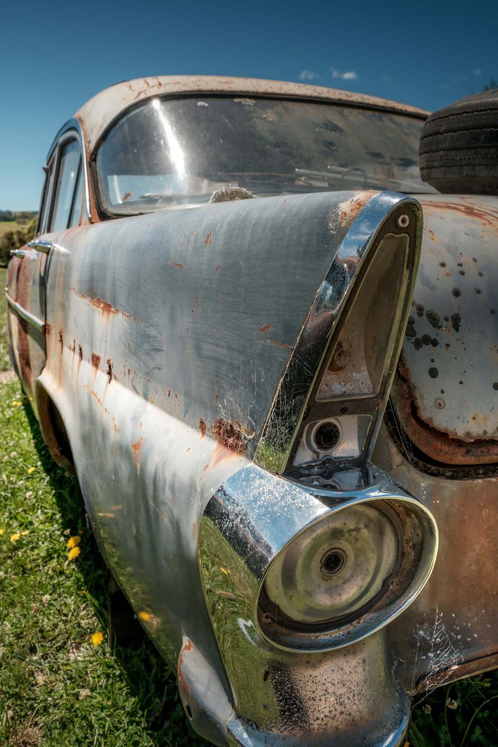 an old rusted out car sitting in a field