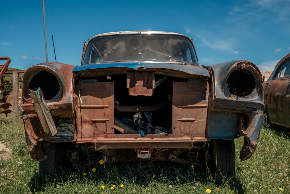 an old rusty car sitting in the grass