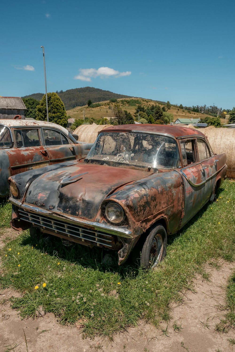 an old rusty car sitting in the grass