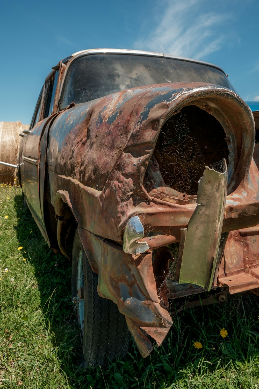 a rusted out car sitting in the grass