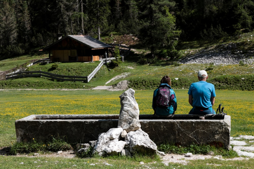 a couple of people sitting on a stone bench