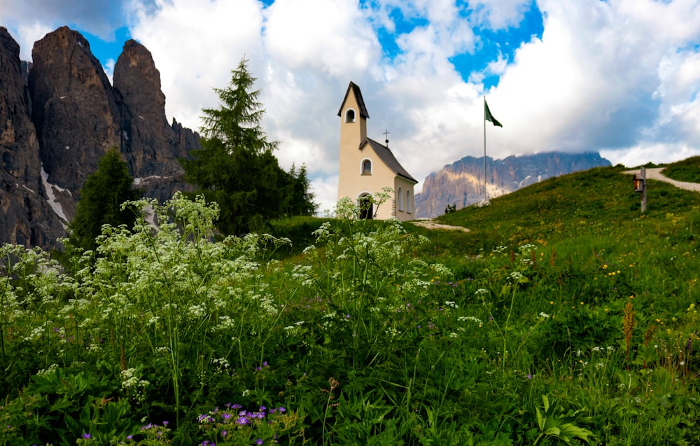 a church in the middle of a field with mountains in the background
