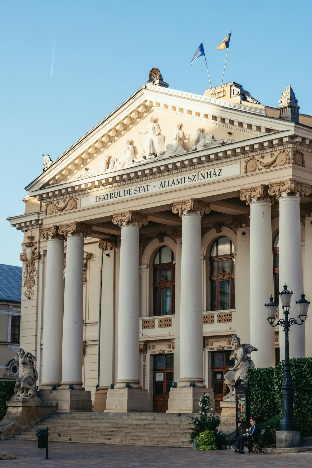 a large building with columns and flags on top of it