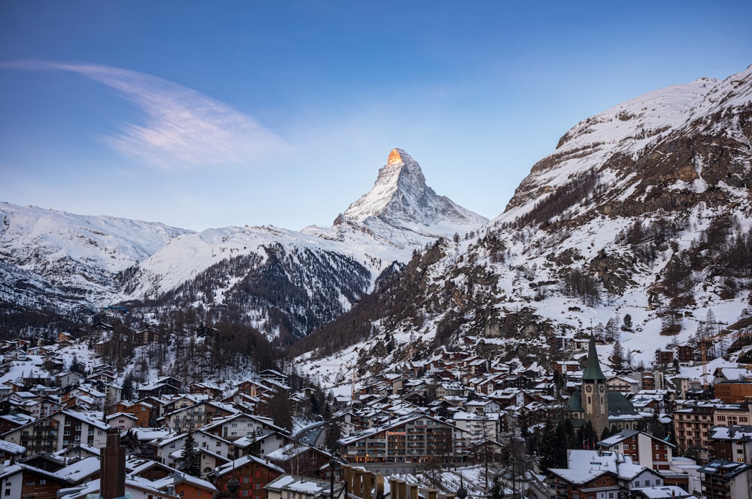 a snowy mountain with a village below it, View of the Matterhorn from Zermatt
