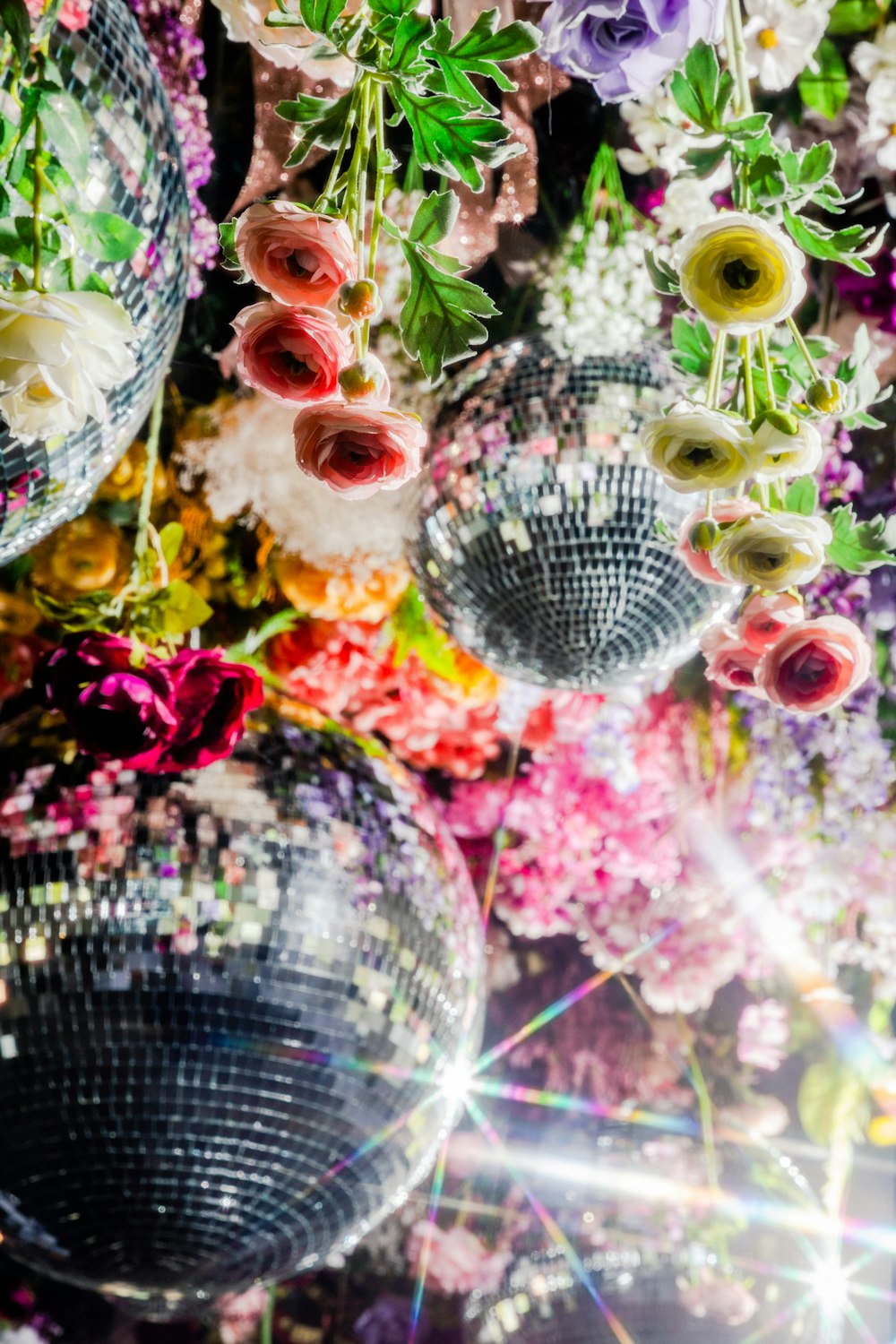a group of disco balls sitting next to a bunch of flowers