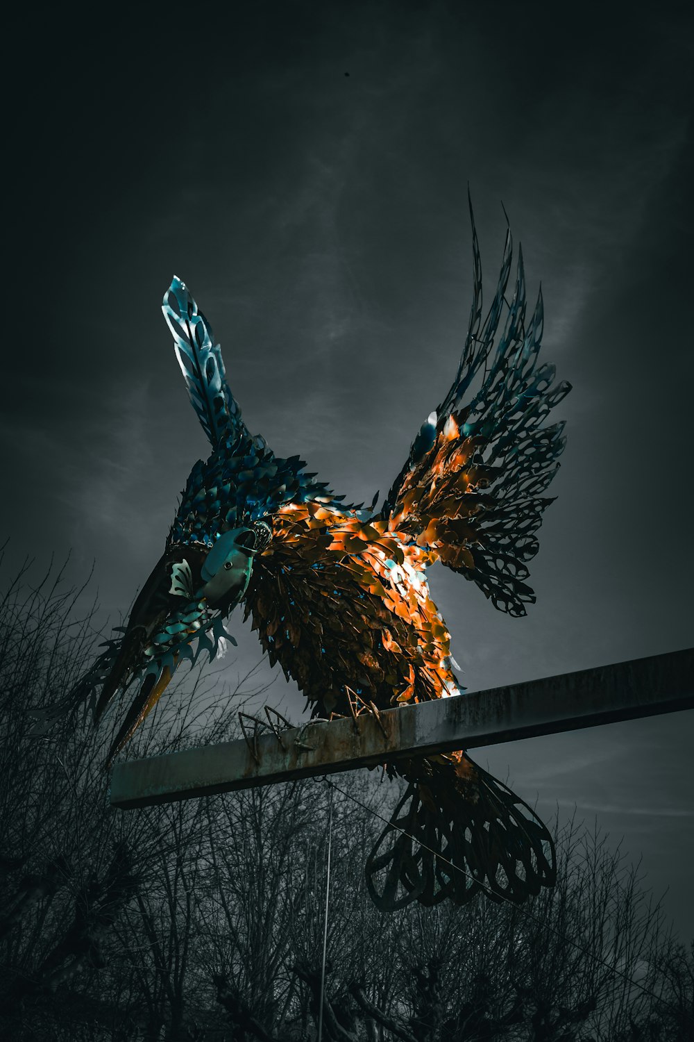 a large metal bird sculpture sitting on top of a metal pole