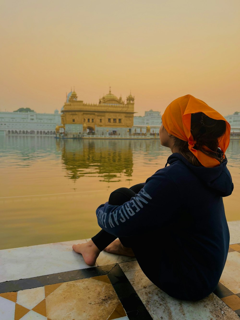 a person sitting on a ledge looking at a body of water