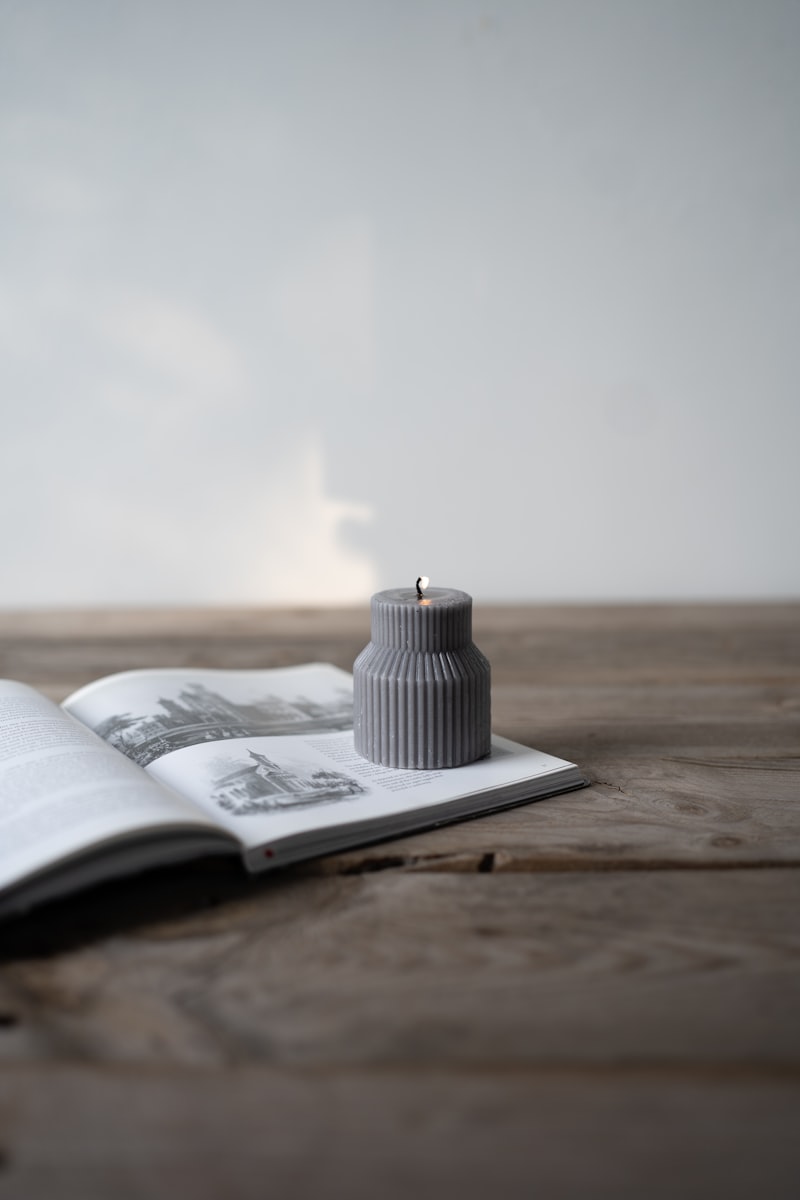 A small candle resting on an open book in soft, quiet light