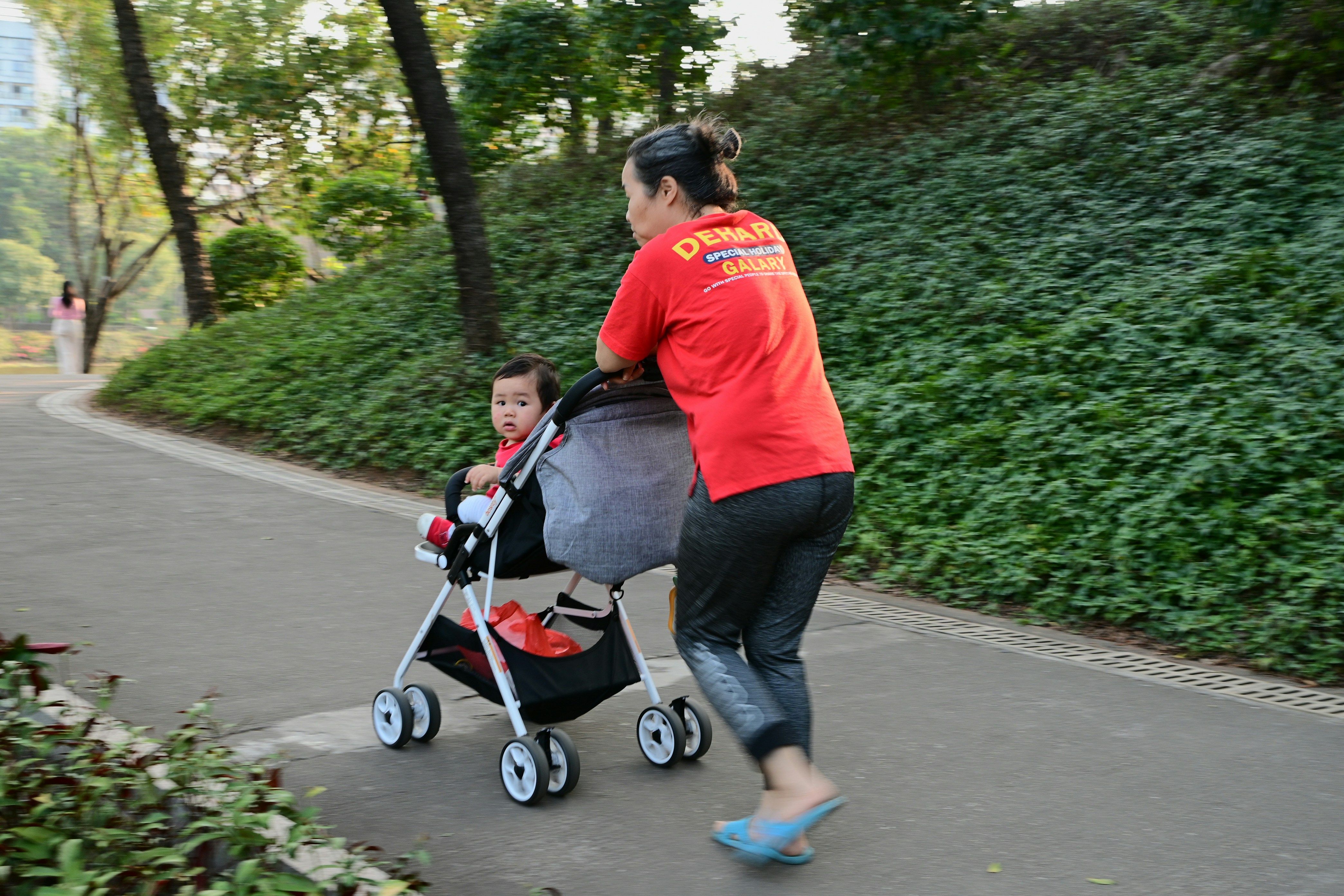 Mother walking with a stroller on a sunny park path to support mood