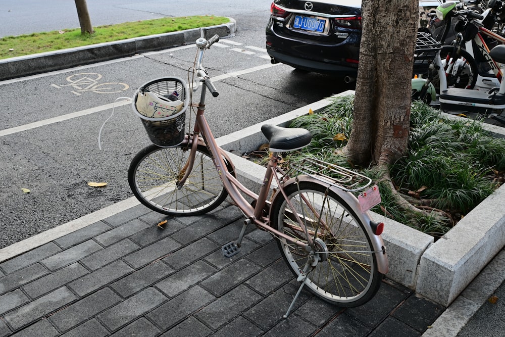 a pink bicycle parked next to a tree on a sidewalk