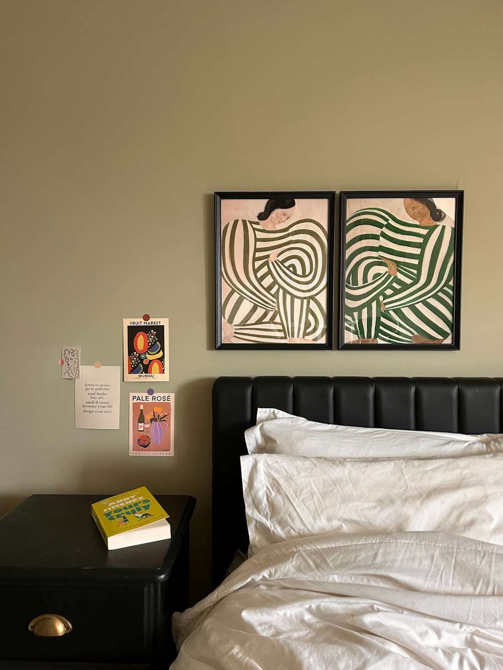a bed with a white comforter and two pictures on the wall