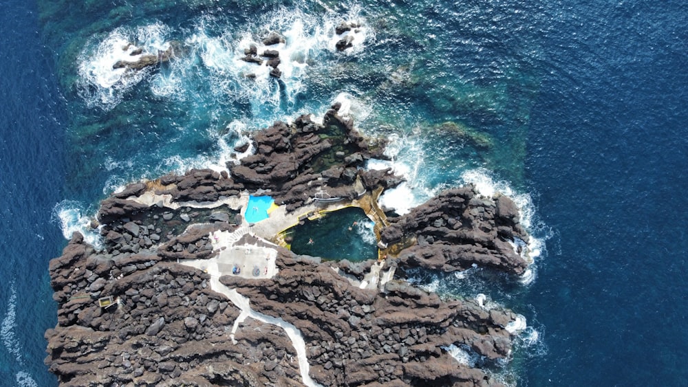 an aerial view of a rocky coastline with a pool