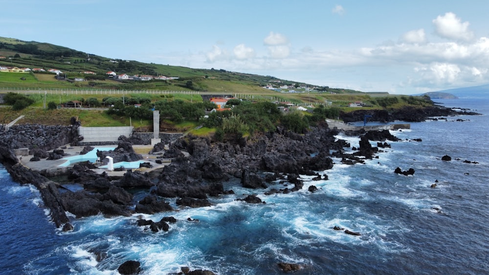 a large body of water next to a lush green hillside