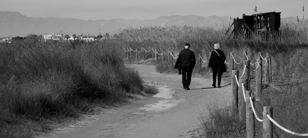 a couple of people walking down a dirt road