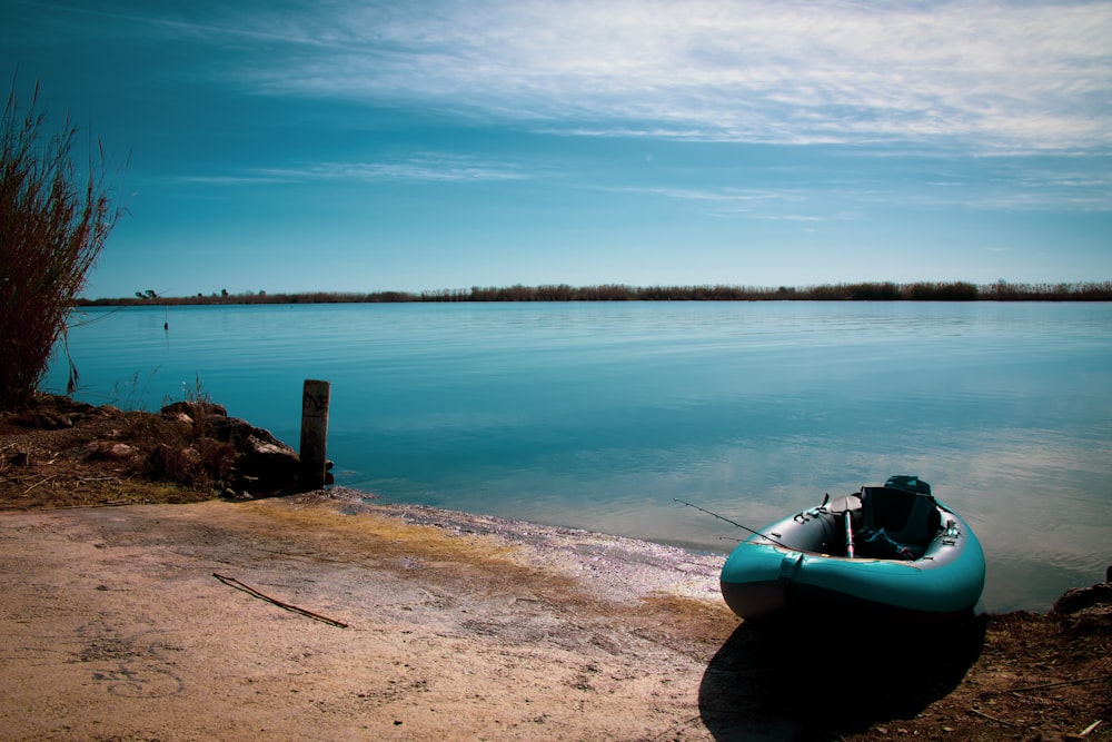 a small boat sitting on the shore of a lake