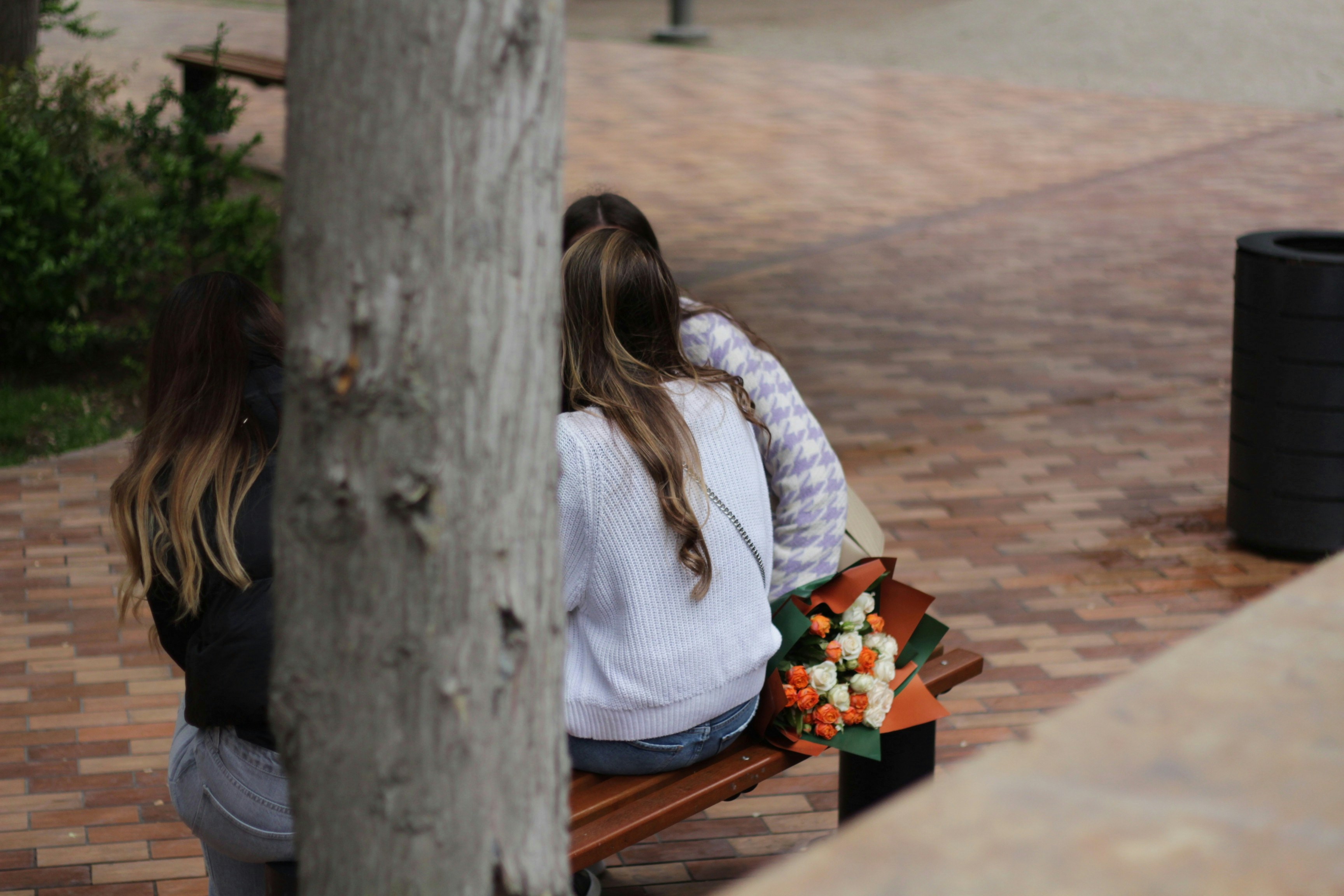 two women sitting on a bench with flowers
