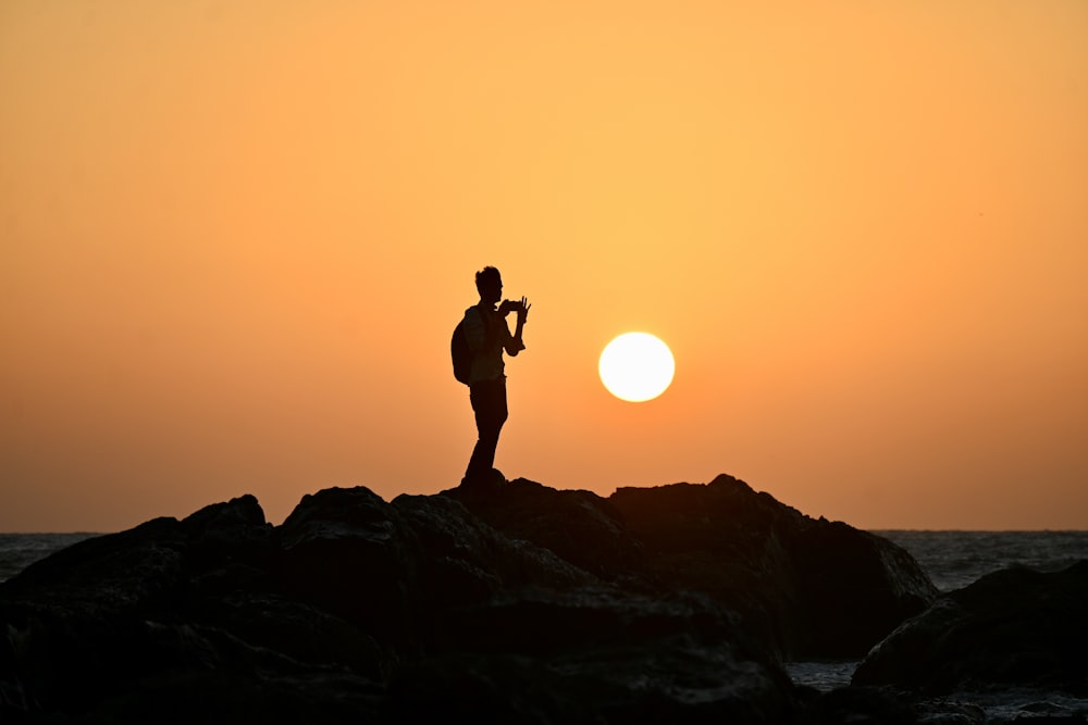 un uomo in piedi sulla cima di una roccia vicino all'oceano