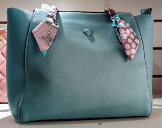 a blue purse with a pink polka dot scarf on it