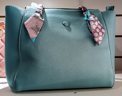 a blue purse with a pink polka dot scarf on it