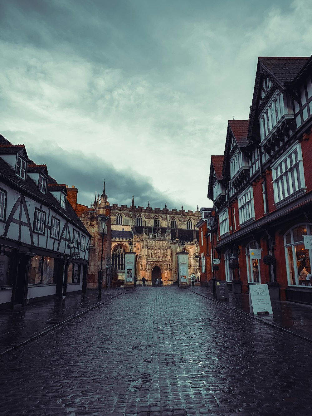 a cobblestone street lined with buildings under a cloudy sky