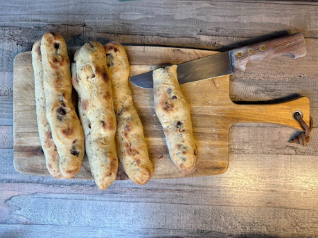 a wooden cutting board topped with sausages next to a knife