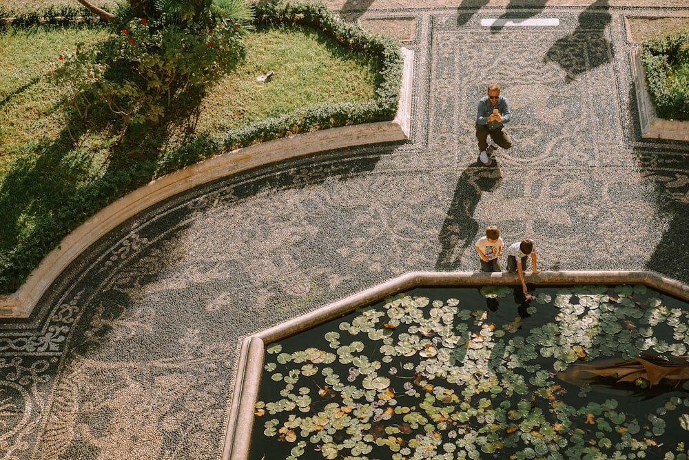 a couple of people standing next to a pond